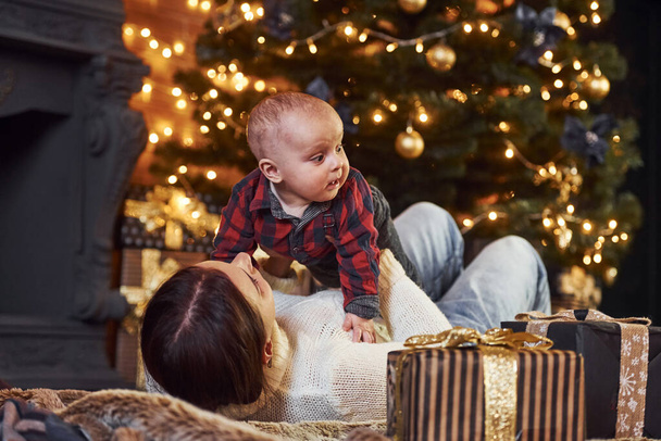 Mother with her little son celebrating new year and christmas holidays indoors. - 写真・画像