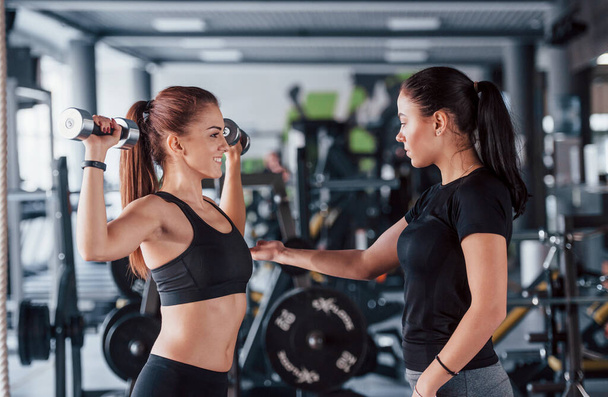Female personal trainer helping woman doing exercises in the gym. - Foto, Imagem