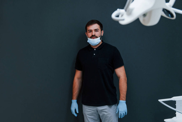Portret van tandarts in handschoenen die binnen in de kliniek staan. - Foto, afbeelding