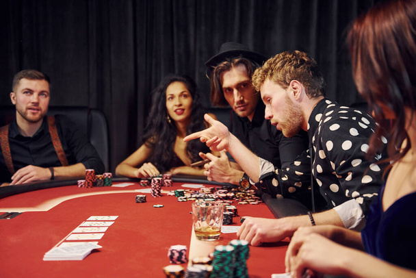 With glasses of drink. Group of elegant young people that playing poker in casino together. - Fotoğraf, Görsel