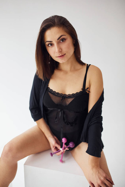 Close up view of woman that sits in black sexy clothes, with vaginal balls and imbuilding tools in the room. - Zdjęcie, obraz