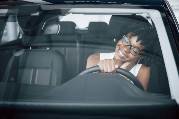 Young african american woman sits inside of new modern car. - Valokuva, kuva
