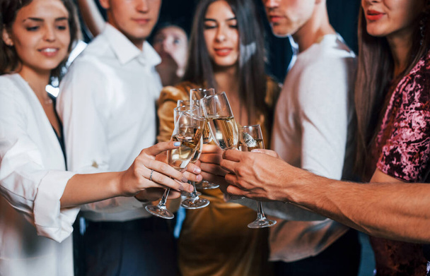 Knocking glasses. Group of cheerful friends celebrating new year indoors with drinks in hands. - Photo, Image