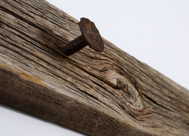 rezavý kovaný hřebík zatlučený do staré suché desky - Fotografie, Obrázek