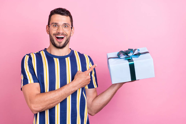 Photo portrait man in glasses amazed pointing at gift isolated pastel pink color background - Φωτογραφία, εικόνα