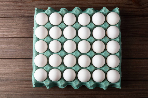 Carton of fresh eggs isolated on wooden background - Foto, imagen