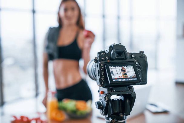 Female vlogger with sportive body standing indoors near table with healthy food. - Foto, Bild
