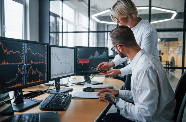 Analyzing information together. Two stockbrokers in formal clothes works in the office with financial market. - Photo, Image