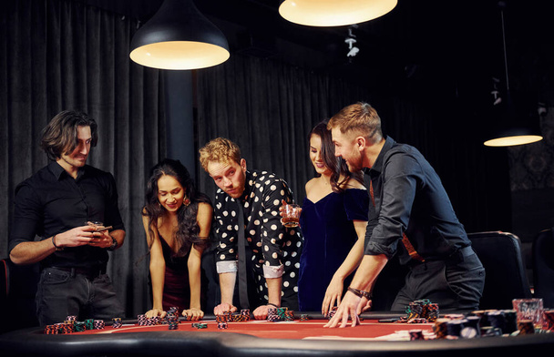 People in elegant clothes standing and playing poker in casino together. - Foto, immagini