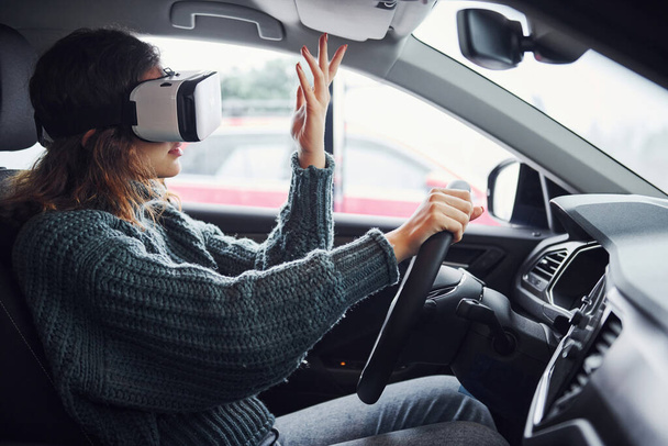 Side view of woman in virtual reality glasses that sitting inside of modern car. - 写真・画像
