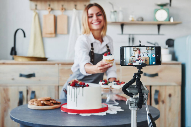 Woman makes delicious sweets and pie. Recording process by smartphone on tripod. - Foto, afbeelding