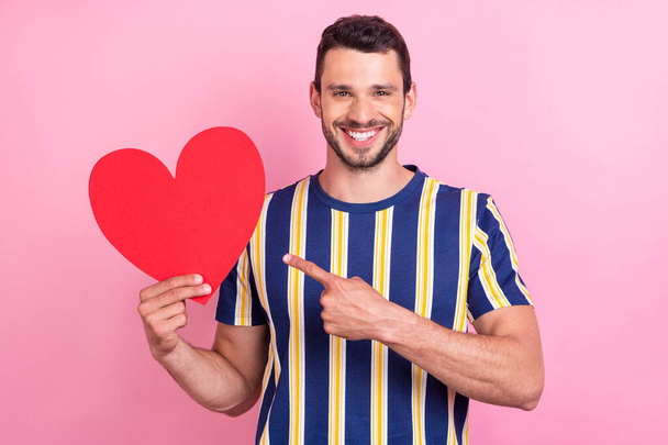 Foto von flippigen Millennial Brunet Kerl Punkt Herz tragen gestreifte T-Shirt isoliert auf rosa Hintergrund - Foto, Bild