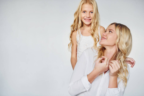 Η μητέρα με την κόρη της διασκεδάζουν μαζί στο στούντιο με λευκό φόντο. - Φωτογραφία, εικόνα