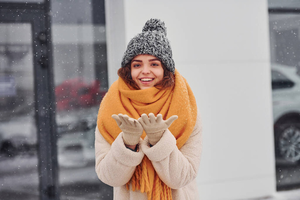 Cheerful young girl smiling standing and smiling outdoors. Snow is falling. - Foto, immagini