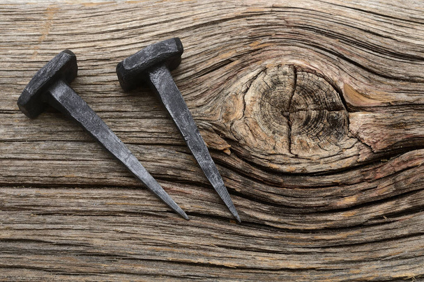 two iron forged nails on a wooden background - Photo, Image