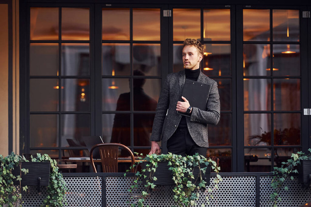 Man in elegant formal wear outside against modern building. - Fotó, kép