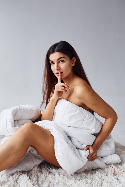 Silence gesture. Finger near the lips. Woman in underwear in the studio against white background. - Foto, imagen