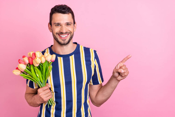 Photo portrait man keeping tulips bouquet showing copyspace isolated pastel pink color background - Foto, Bild