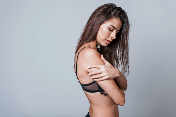 Sexy woman in black underwear standing in the studio against grey background. - 写真・画像