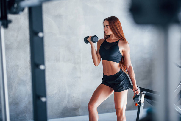 Young fitness woman is in the gym with dumbbells in hands. - Foto, Bild