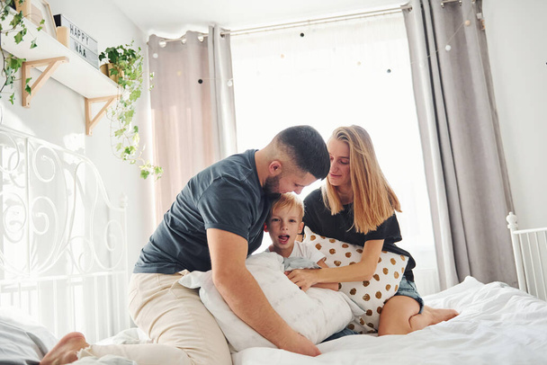 Young married couple with their young son have leisure together in bedroom at daytime. - Valokuva, kuva