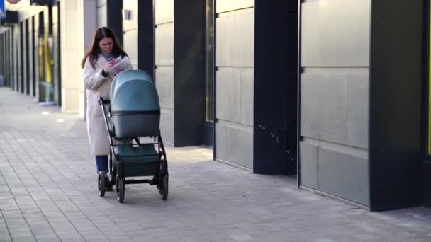 Jeune mère avec poussettes bébé en ville marche - Séquence, vidéo