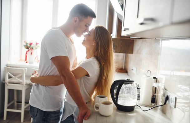 Young couple at morning together standing on the modern kitchen. - 写真・画像