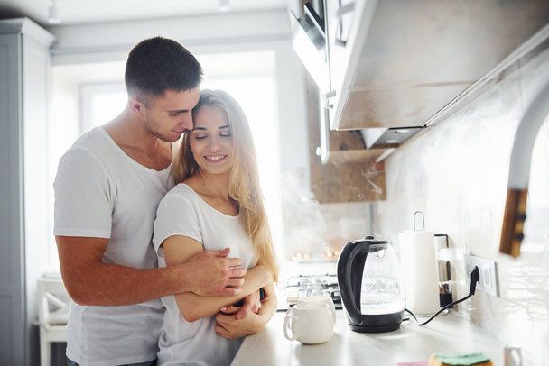 Young couple at morning together standing on the modern kitchen. - Foto, Imagem
