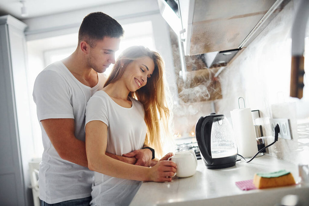 Young couple at morning together standing on the modern kitchen. - Foto, Bild