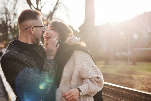 Cheerful multiracial couple embracing each other outdoors in the city. Asian girl with her caucasian boyfriend. - 写真・画像