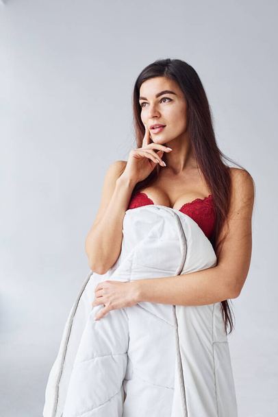 Woman in red underwear covering her body by towel in the studio against white background. - Foto, immagini