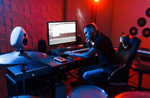 Sound engineer working and mixing music indoors in the studio near drum kit. - 写真・画像