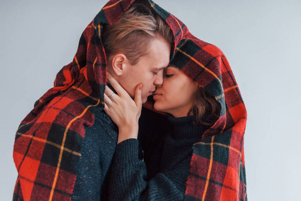 With red towel. Cute young couple embracing each other indoors in the studio. - Photo, image