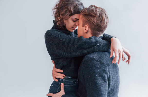 Cute young couple embracing each other indoors in the studio. - Photo, Image