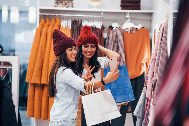Looking for a warm clothes. Two young women have a shopping day together in the supermarket. - Foto, Imagen