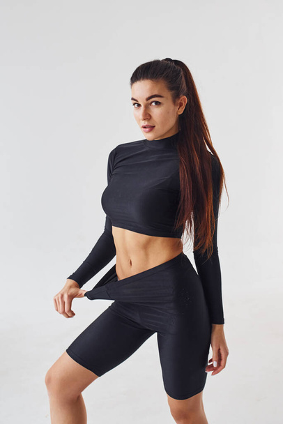 Sportive woman in black clothes in the studio against white background. - Foto, immagini