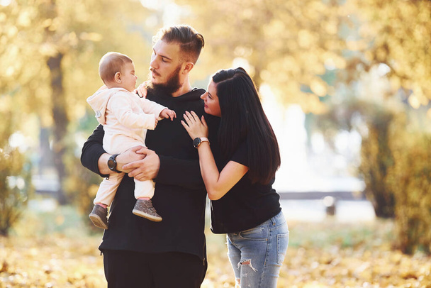 Cheerful family having fun together with their child in beautiful autumn park. - Fotoğraf, Görsel