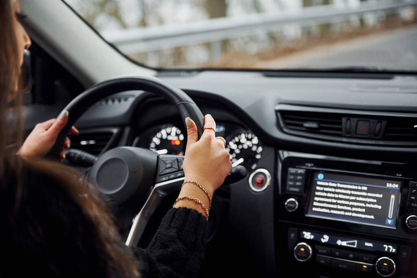 Rear view of brunette female driver that riding modern car at daytime. - Фото, зображення