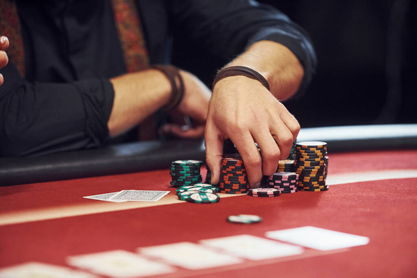 Close up view of man's hands. Guy plays poker game by table in casino. - Foto, Imagen