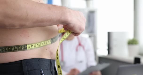 Hombre midiendo su cintura con cinta en la cita con el médico película 4k - Metraje, vídeo