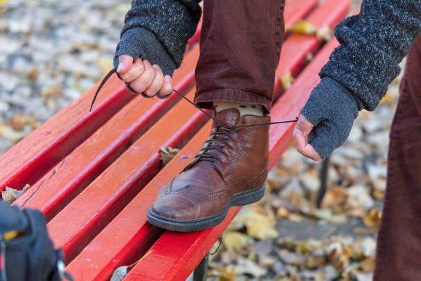 A man is tying laces on brown shoes - 写真・画像
