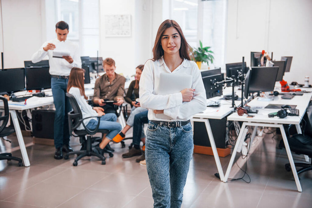 Beautiful young girl indoors in office against her coworkers in the office. - Foto, Bild