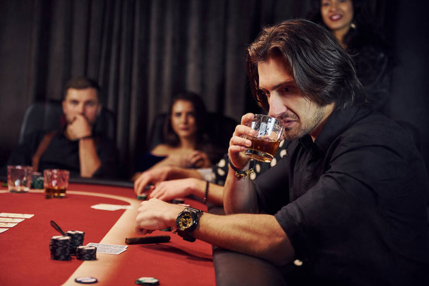 Group of elegant young people that playing poker in casino together. - Фото, изображение