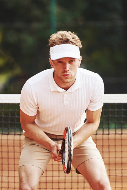 Young tennis player in sportive clothes is on the court outdoors. - Fotó, kép