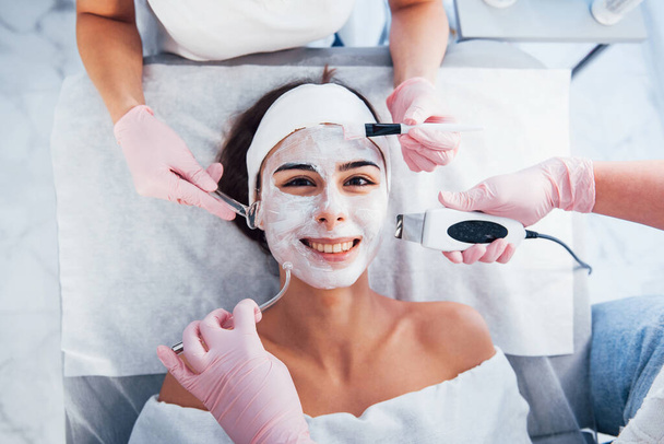 Close up view of woman that lying down in spa salon and have face cleaning procedure by different devices and mask. - Foto, Imagem