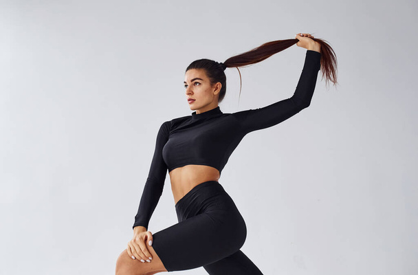 Sportive woman in black clothes in the studio against white background. - Foto, immagini