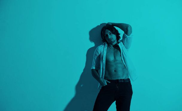 Portrait of young hot man that stands in neon lights in the studio. - Fotó, kép