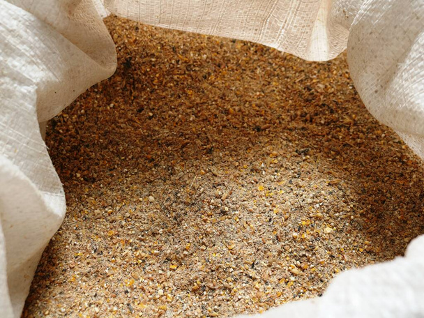 crushed compound feed for farm animals and poultry domans in an open sack made of burlap, feed mixture of bran, wheat, corn and cake for complete feeding of livestock - Foto, imagen