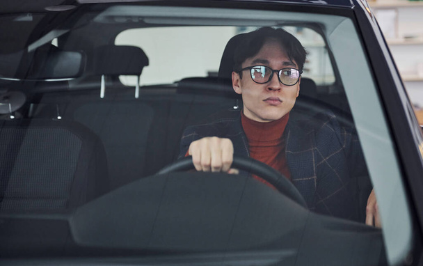 Man in eyewear and formal clothes sitting inside of modern car. - 写真・画像