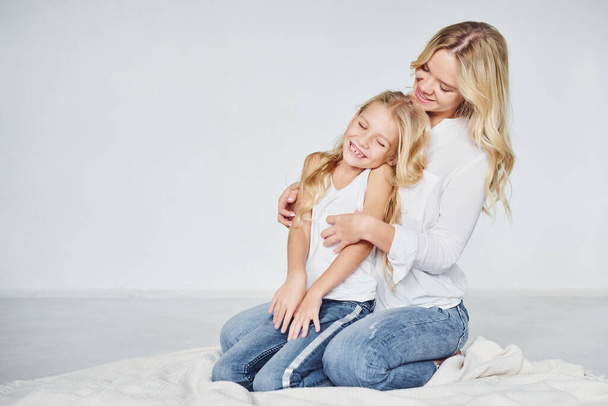 Closeness of the people. Mother with her daughter together in the studio with white background. - Foto, Imagen